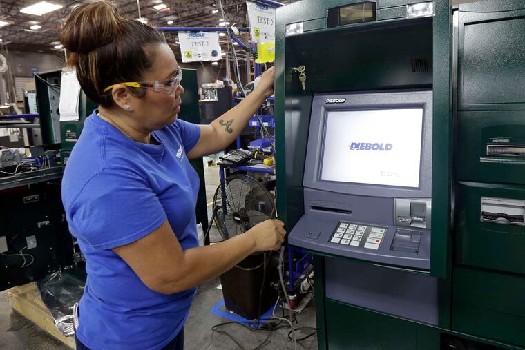 Maria Edney installs software onto an automated teller machine at Diebold Nixdorf, the world's largest maker of ATMs, in Greensboro, N.C.