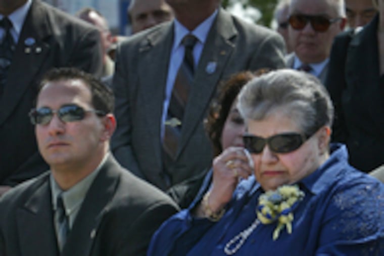 Elizabeth Galdi (right), widow of slain officer Ralph Galdi, wipes away tear during plaque ceremony. Her son, Ray, sits beside her.