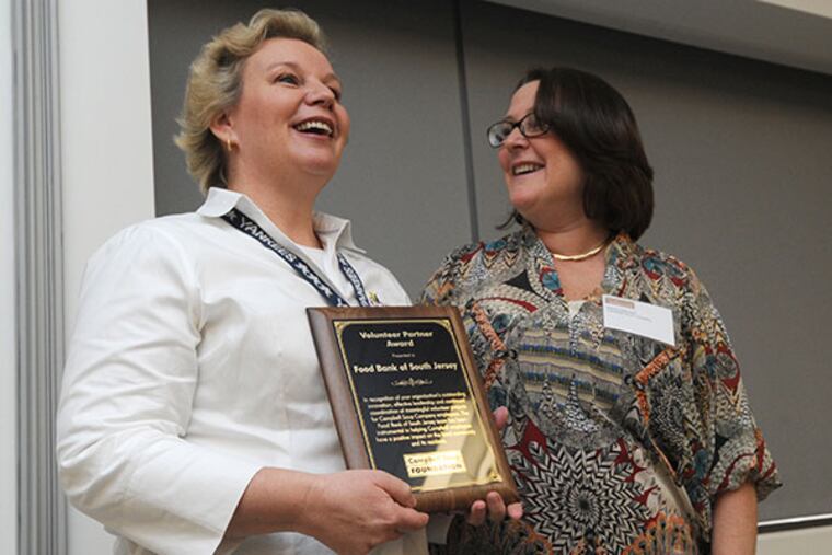 Sabine Mehret, Community Engagement Manager for the Food Bank of South Jersey, accepts the Volunteer Partner Award from Wendy Milanese of Campbells for the Food Bank's contributions to Camden on Jan. 15, 2014, at the company’s Networking Breakfast Awards ceremony. ( APRIL SAUL / Staff )