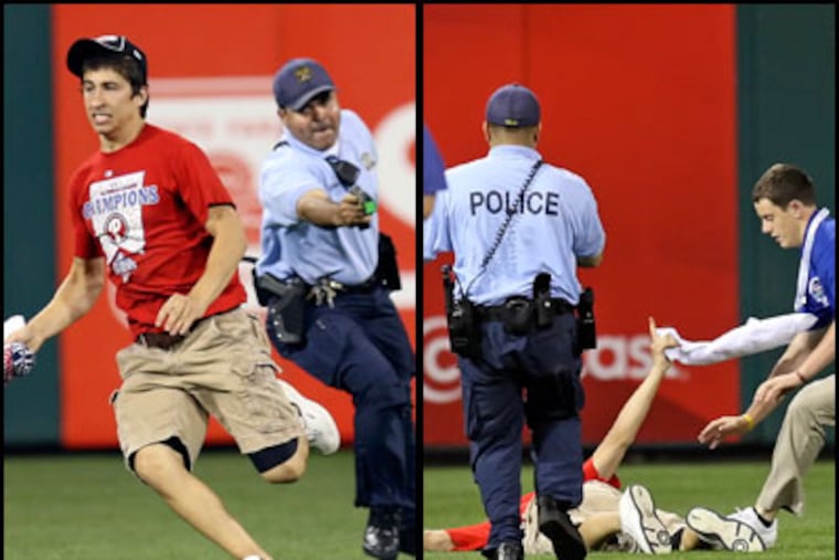 A Philadelphia police officer with Taser in hand chases a Phillies' fan, now identified as Steve Consalvi, who ran on the field during Monday night's game. Consalvi was felled by a taser. (Steven M. Falk / Staff Photographer)