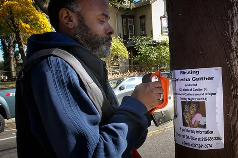 Carl Freeland, father of Carlesha Gaither of Germantown staples a flyer with information on his missing daughter allegedly abducted from W. Coulter St at Greene St. on Sunday, November 2, 2014. ( ALEJANDRO A. ALVAREZ / STAFF PHOTOGRAPHER )