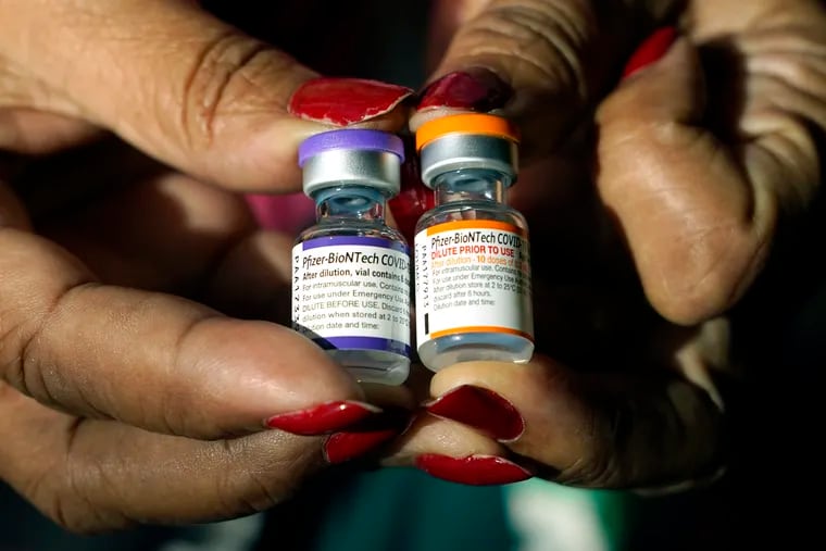 A nurse holds a vial of the Pfizer COVID-19 vaccine for children ages 5 to 11, right, and a vial of the vaccine for adults, which has a different colored label, at a vaccination station in Jackson, Miss.