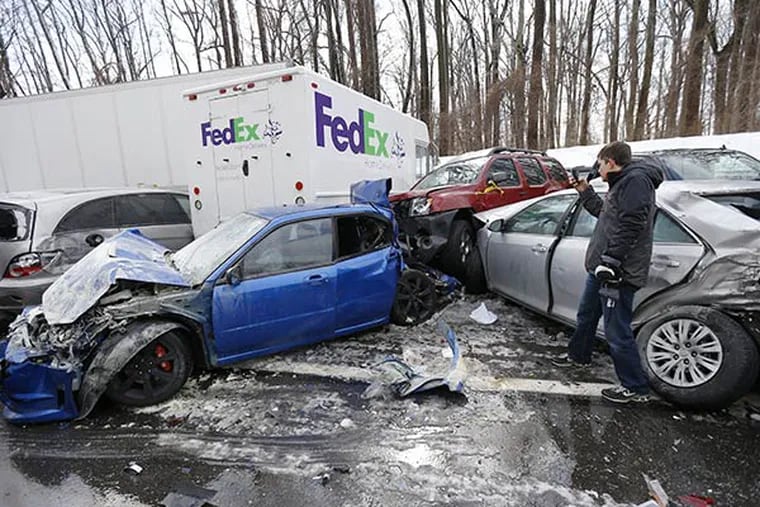 A man inspects vehicles piled up in an accident, Friday, Feb. 14, 2014, in Lower Southampton. Traffic accidents involving multiple tractor trailers and dozens of cars completely blocked one side of the Pennsylvania Turnpike outside Philadelphia for several hours and caused some injuries. (AP Photo/Matt Rourke)