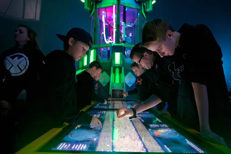 Recruits young and old are tasked to help piece together the Super Adaptoid with touch screen monitors. (File photo)