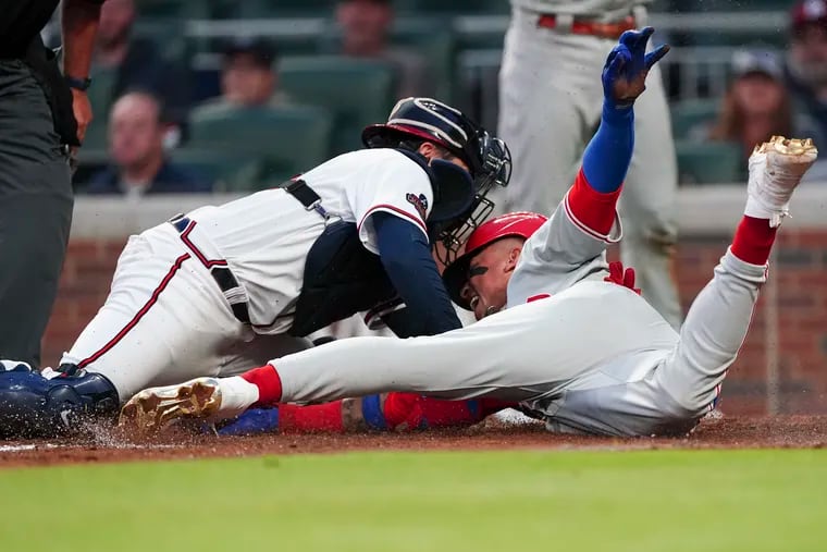 The Phillies' Johan Camargo beats the tag from Atlanta Braves catcher Travis d'Arnaud to score on a two-run double by Roman Quinn in the third inning.