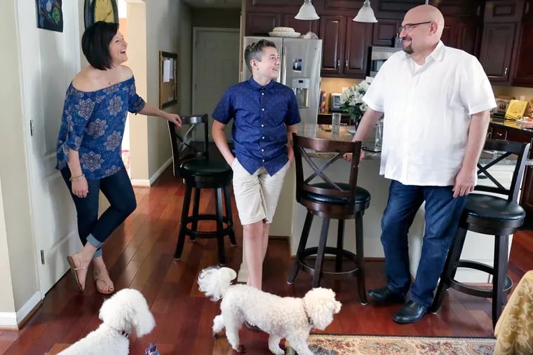 Mason Catrambone, 14, with father Frank Catrambone and his fiancee Annmarie Kita, along with family dogs Chooch and Chloe, in the kitchen of their Williamstown home.