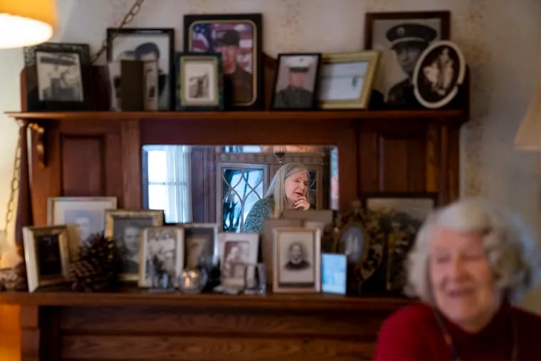 Nancy Rose, center in mirror, speaks with her mother, Amy Russell, right, who both contracted COVID-19 in 2021, in their dining room surrounded by pictures of relatives and family in Port Jefferson, N.Y.