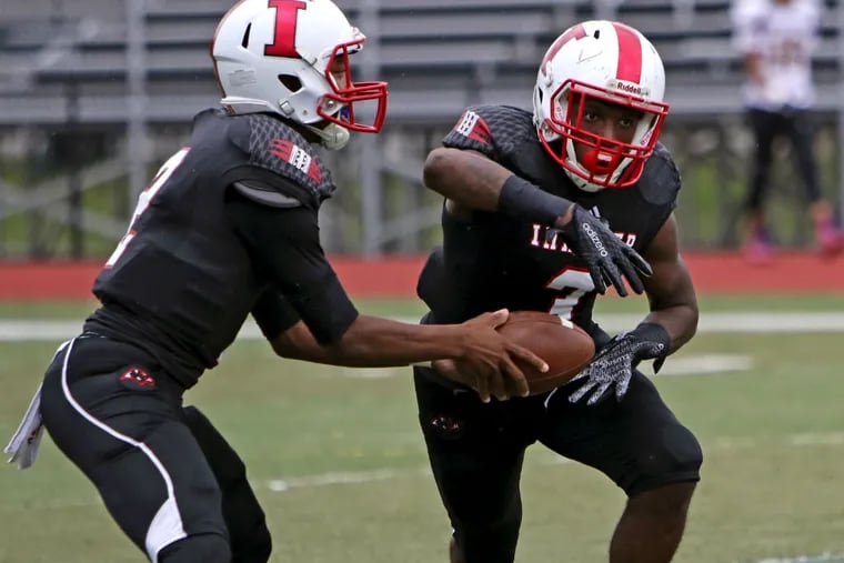 Imhotep Charter quarterback Nasir Boykins (2) hands the ball off to Isheem Young (3) during their high school football game against St. Francis, Saturday Sept. 12, 2015, in Philadelphia. Imhotep Charter defeated St. Francis 40-16.