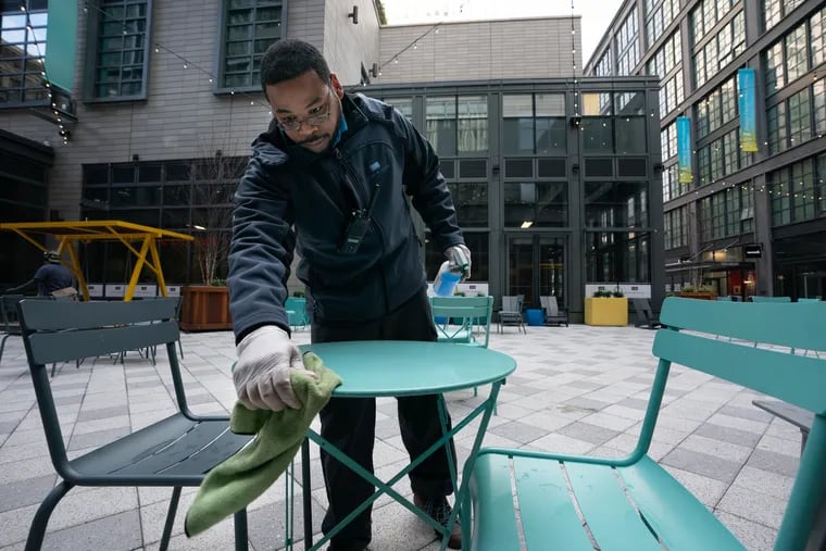 Chris, who prefers to be identified by his first name only, wipes down tables on the 1100 block of Market Street, in Philadelphia, March 17, 2020, on the first day of the shutdown of nonessential businesses.