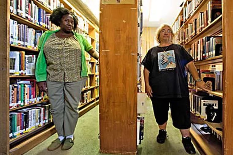 Ethel Randall (left) and Barbara Park have worked together at the Fairview branch for 18 years. They’ll move to different libraries. (DAVID M WARREN / Staff Photographer)