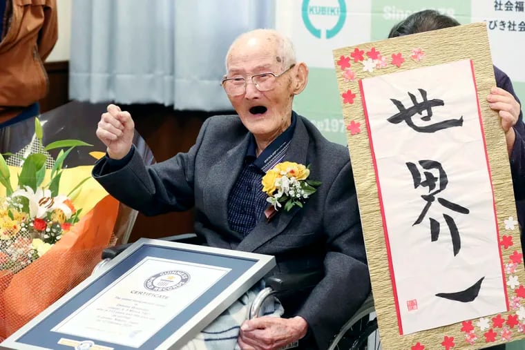 Chitetsu Watanabe, 112, poses next to the calligraphy he wrote after being awarded as the world's oldest living male by Guinness World Records, in Joetsu, Niigata prefecture, northern Japan. The Japanese man who received his certificate as the world's oldest man with a raised fist and big smiles earlier this month has died at 112.
