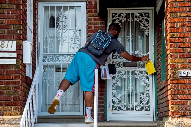 Eddie Howard, a canvasser with Community Marketing Concepts, a marketing consultant group contracted by the city's Department of Revenue, goes door-to-door in Ogontz August 23, 2018 leaving information packets and talking to homeowners about tax relief programs. TOM GRALISH / Staff Photographer