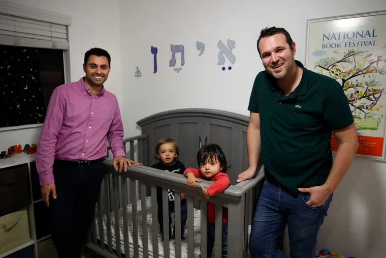 FILE - In this Tuesday, Jan. 23, 2018, file photo, Elad Dvash-Banks (left) and his partner, Andrew, pose for photos with their twin sons, Ethan (center right) and Aiden in their apartment in Los Angeles. A federal judge in California has ruled that a twin son of the gay couple has been an American citizen since birth, handing a defeat to the U.S. government, which had only granted the status to his brother. District Judge John Walter said Thursday, Feb. 21, 2019, that the State Department was wrong to deny citizenship to 2-year-old Ethan Dvash-Banks.