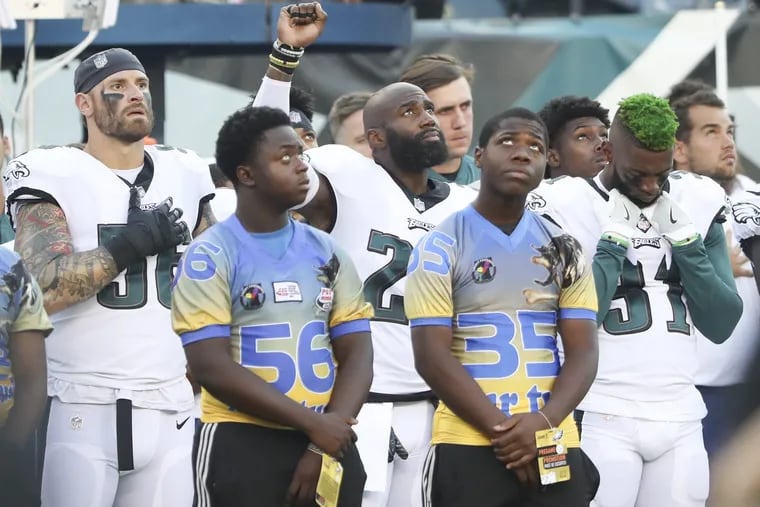 Eagles defensive back Malcolm Jenkins raises his fist next to teammate defensive end Chris Long and defensive back Jalen Mills during the national anthem before the Eagles' game against the Steelers on Thursday.