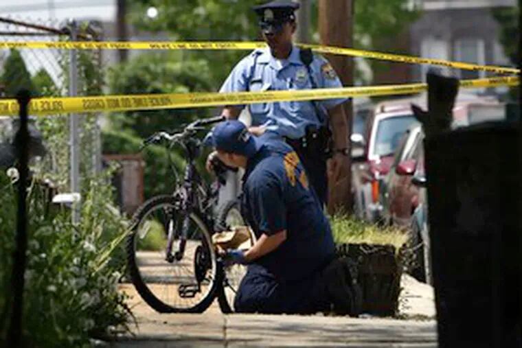 Police dust a bicycle for fingerprints while investigating an alleged home invasion try in Southwest Philly.