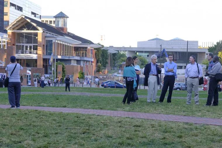 As evening descends on Independence Mall, small groups of visitors gather on the lawn.