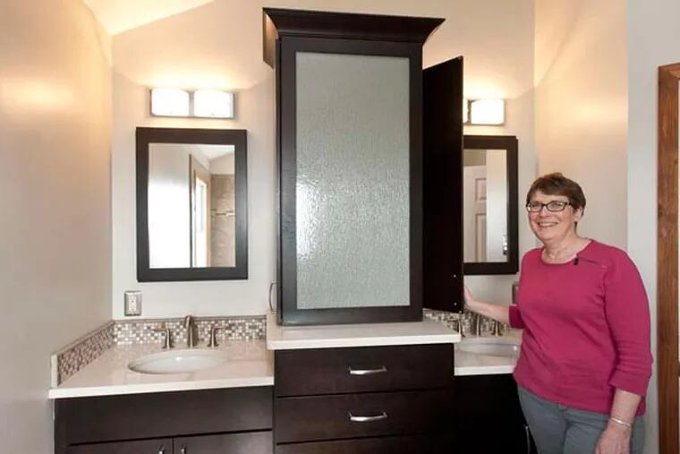 Stacey Starcher in the redone master bath in her Doylestown home. The custom cherry cabinets got a dark finish to match the room's teak accents.