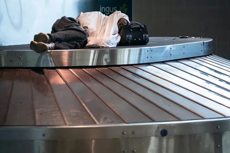A man sleeps on a baggage carousel in the baggage claim area of terminal A at the Philadelphia International Airport on Wednesday.