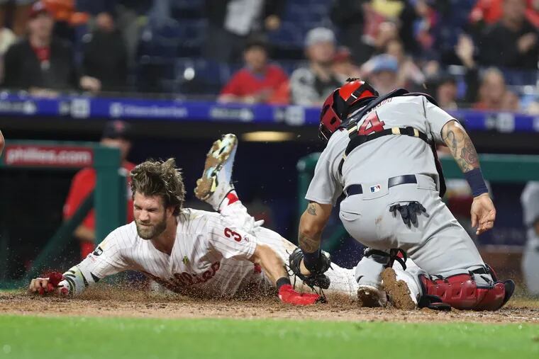 Bryce Harper, left, of the Phillies is thrown out at home on a throw from centerfielder Harrison Bader, not pictured, to catcher Yadier Molina, right, of the Cardinals at Citizens Bank Park on May 28, 2019.    He tried to score on a hit by Rhys Hoskins.