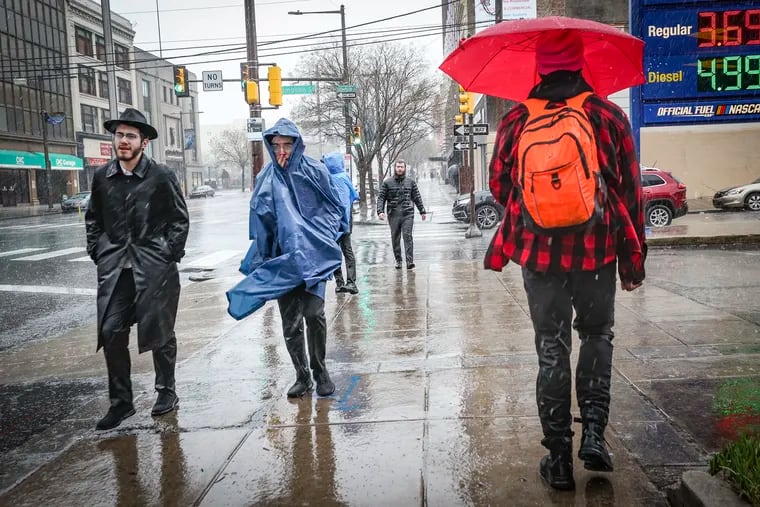 Pedestrians walk along Broad Street near Thompson Street in North Philadelphia on Saturday during the rainiest March day in Philly's history.