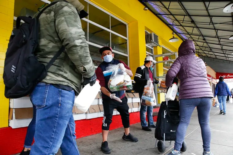 Miguel Vera Peña hands a despensa (a pack of food for Central American and Mexican populations) to a person waiting for the donation at the Los Taquitos de Puebla III in South Philadelphia on Thursday, April 30, 2020.