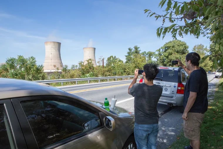 Passersby stop to photograph the cooling towers of Three Mile Island Unit 1 in Middletown, Pa., Friday, the reactor's last day of operation.