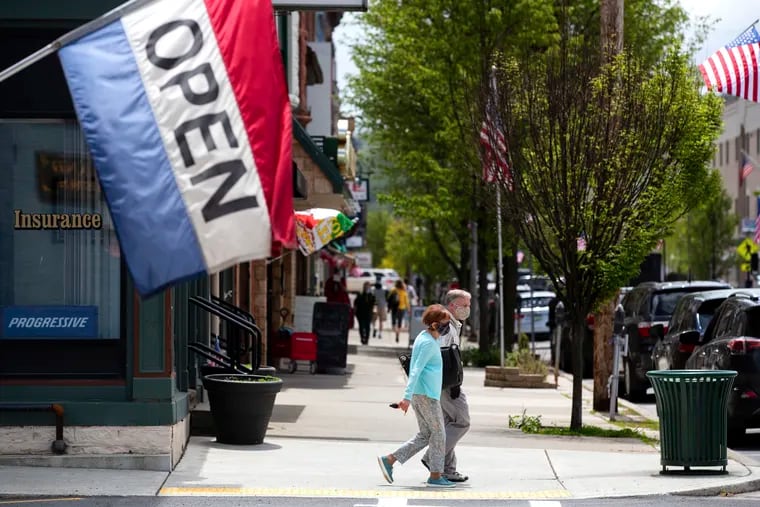 People wear masks along Main Street in Honesdale, Pa. Pennsylvania’s unemployment began sliding down from its pandemic peak in May, even clocking in at below the national rate as payrolls grew by almost 200,000, the state said Friday.