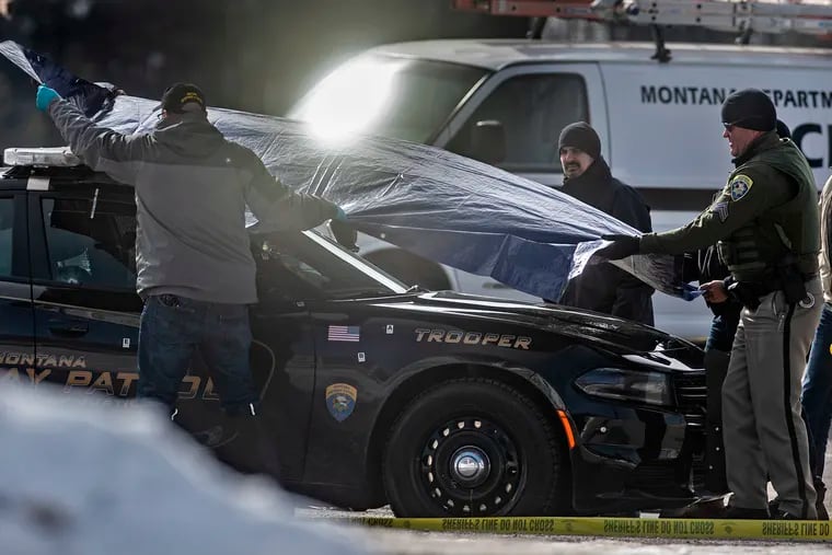 Law enforcement cover Montana State Trooper Wade Palmer's car at the scene of the shooting near the Evaro Bar on Friday, March 15, 2019, in Missoula, Mont. Palmer, who was investigating an earlier shooting, was himself shot and critically injured early Friday after finding the suspect's vehicle, leading authorities to launch an overnight manhunt that ended in the arrest of a 29-year-old man, officials said. (Tommy Martino / The Missoulian via AP)