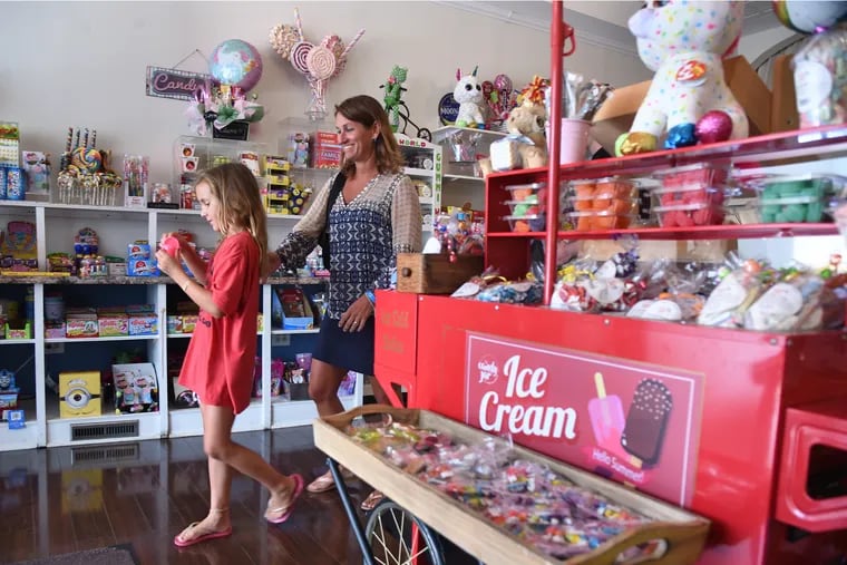 Amy Undlin (right) and her daughter Taylor, 9, of Haddonfield leave the Candy Jar by 1892 in downtown Collingswood during their "Lights On" shop local week and restaurant week July 31, 2019.  Many downtowns in South Jersey have had tough seasons due to the heat that has kept many shoppers indoors. But last week's most recent round of storms hit at an especially bad time and closed many restaurants and businesses.