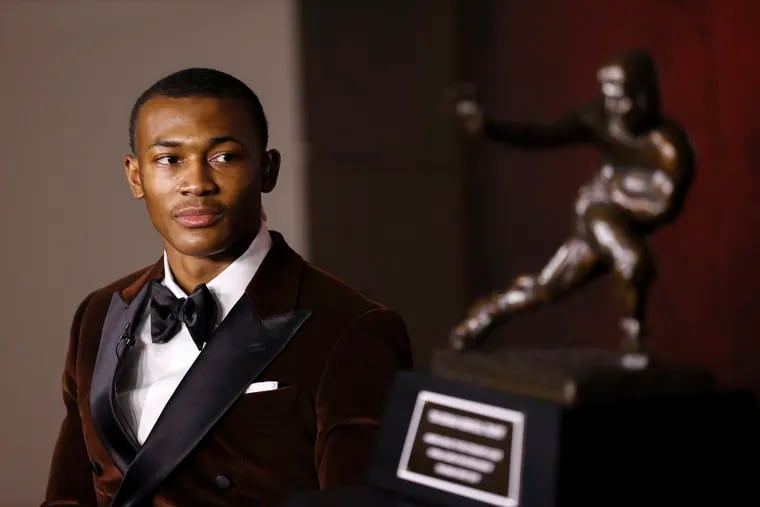 In a photo provided by the Heisman Trophy Trust, Alabama wide receiver DeVonta Smith looks at the Heisman Trophy after being named the winner on Jan. 5.