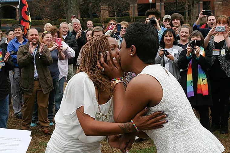 A kiss seals a same-sex marriage at a ceremony in Big Spring Park in Huntsville, Ala. Gay couples were able to get licenses Monday in about a dozen places, including Huntsville and Birmingham. Decatur Daily, via Associated Press