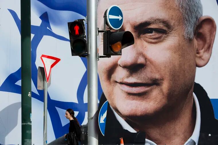 File - In this Thursday, March 28, 2019 file photo, a woman walks by an election campaign billboard showing Israel's Prime Minister Benjamin Netanyahu, the Likud party leader, in Tel Aviv, Israel. An Israeli watchdog said Monday that it's found a network of social media bots disseminating messages in support of Netanyahu ahead of next week's elections.
