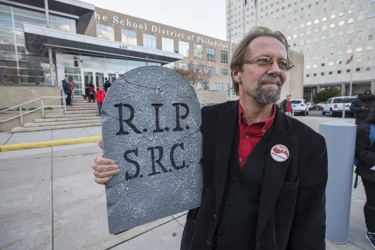 Douglas Leach, a graduate and now a teacher at Lincoln High School, holds a tombstone for the SRC as they rallied outside the School District of Philadelphia Building on Nov. 16, 2017. The School Reform Commission took a historic vote to self-destruct in November 2017. Now, applications are open for a new local school board.