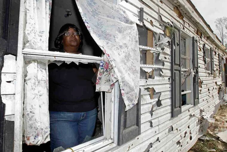 Audrey McKoy looks out a broken window of her destroyed home after 92 tornadoes tore through North Carolina on Saturday.