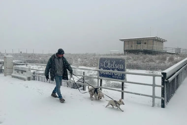 Randy Cherkas of Atlantic City walked his two dogs, Hobo Ricky and Don Pablo, past the Chelsea Beach Bar on a snowy boardwalk on Monday.