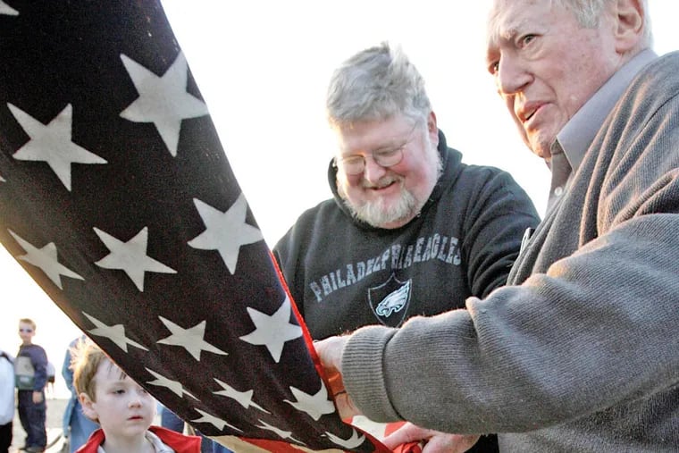 Marvin Hume (right) helps Michael Teiper and son, Jonathan, fold a flag in 2008 that belonged to
Michael’s father, who served in WWII. Hume spent four decades performing similar ceremonies. (ELIZABETH ROBERTSON / STAFF PHOTOGRAPHER)