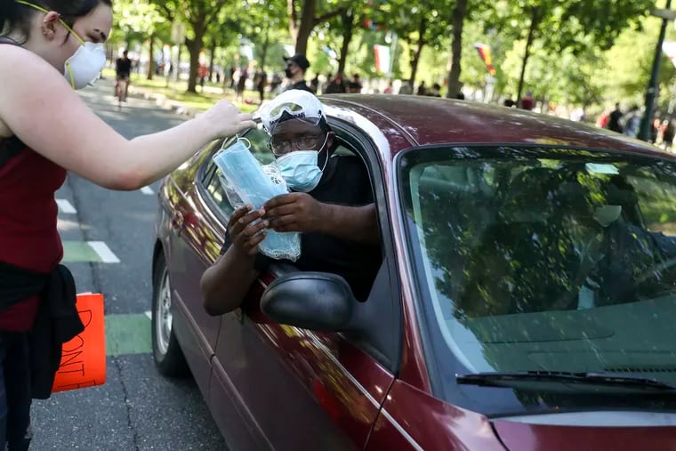 Christopher Aziz Johnson of Philadelphia passes out face masks to protesters on the Ben Franklin Parkway in Philadelphia, Pa. on Monday, June 1, 2020.