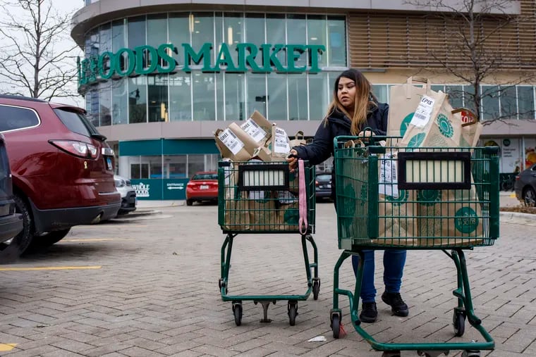 Alid Alvarado transports orders for three different Instacart customers to her car at Whole Foods. (Brian Cassella/Chicago Tribune/TNS)