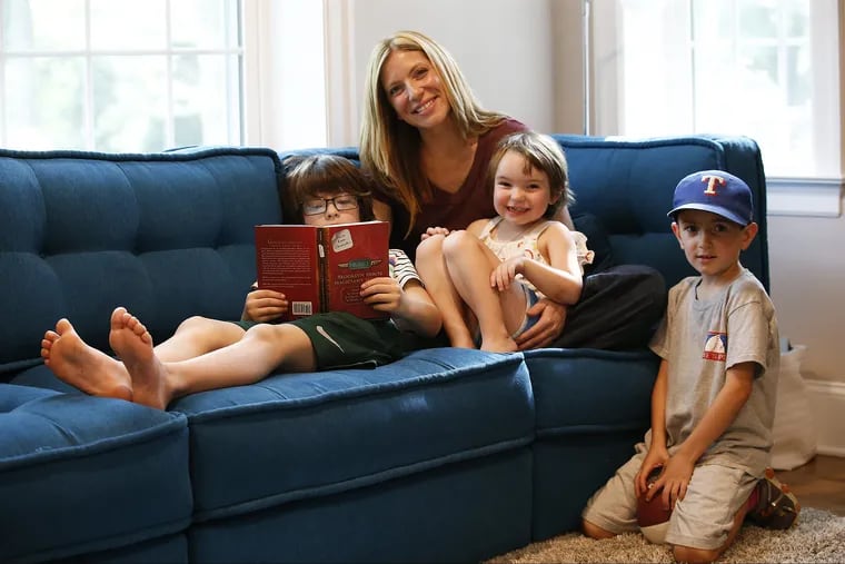 Mother Jennifer Lentz with her kids (right to left) Bryan, 7, Daisy, 4 and Thomas, 9 reading in their Swarthmore home. Lentz has concerns about her children's screen time exposure.