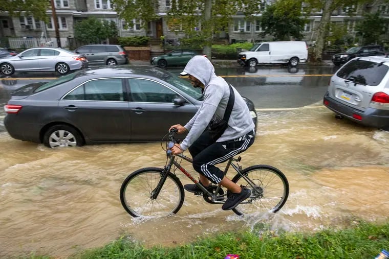 A cyclist commutes in heavy rain along Cottman during a water main break at Walker. The heavy rains didn't help matters.
