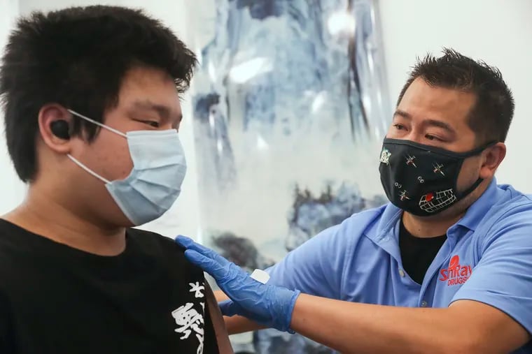 Alan Chen, 14, receives his second dose of the COVID-19 vaccine from pharmacist Allen Lee of SunRay Drugs at the Crane Community Center in July.