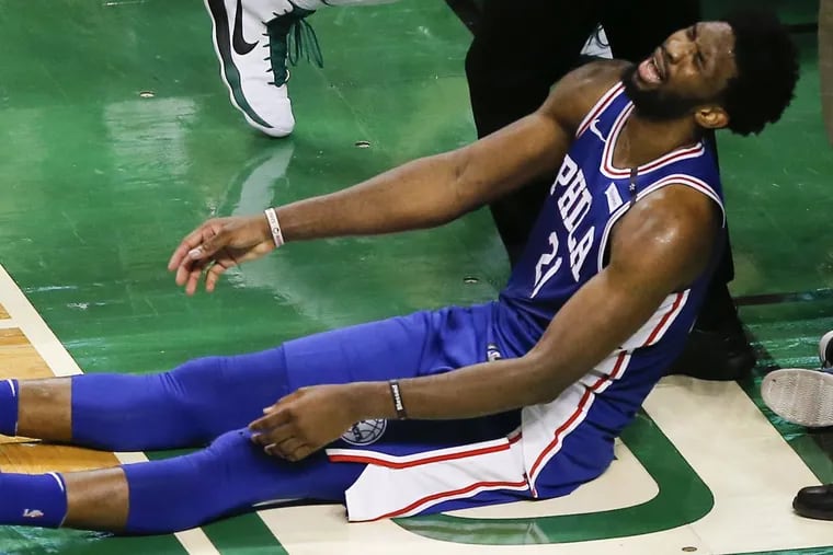 Sixers center Joel Embiid lays on the floor after losing the basketball out of bounds late in the fourth-quarter against the Boston Celtics in game five of the Eastern Conference semifinals on Wednesday, May 9, 2018 in Boston.