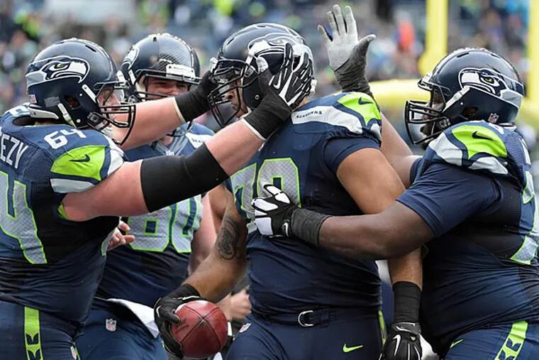 Seattle Seahawks tackle Garry Gilliam (79) celebrates his 19 yard touchdown catch on a fake field goal with J.R. Sweezy (64) and Alvin Bailey (78) against the Green Bay Packers during the third quarter in the NFC Championship Game at CenturyLink Field. (Kirby Lee/USA Today)