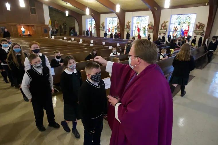 Father Jonathan Dalin sprinkles ashes on children from St. Martha Parish.