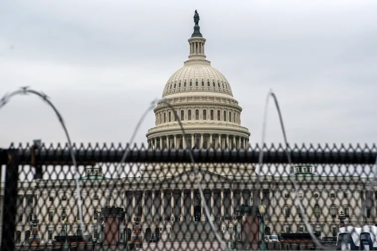 The U.S. Capitol is seen through a fence with barbed wire during the second impeachment trial of former President Donald Trump in Washington on Friday.