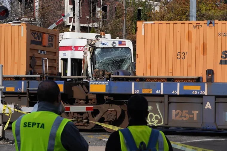 SEPTA workers wait while a train is moved after a trolley crashed into it in Darby on Thursday.