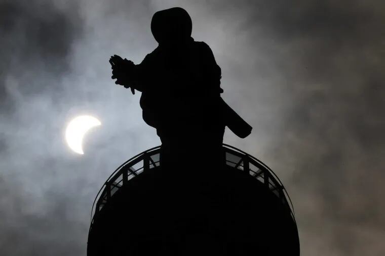 The solar eclipse can be seen beside the statue of William Penn on top of Philadelphia City Hall on Monday, August 21, 2017.