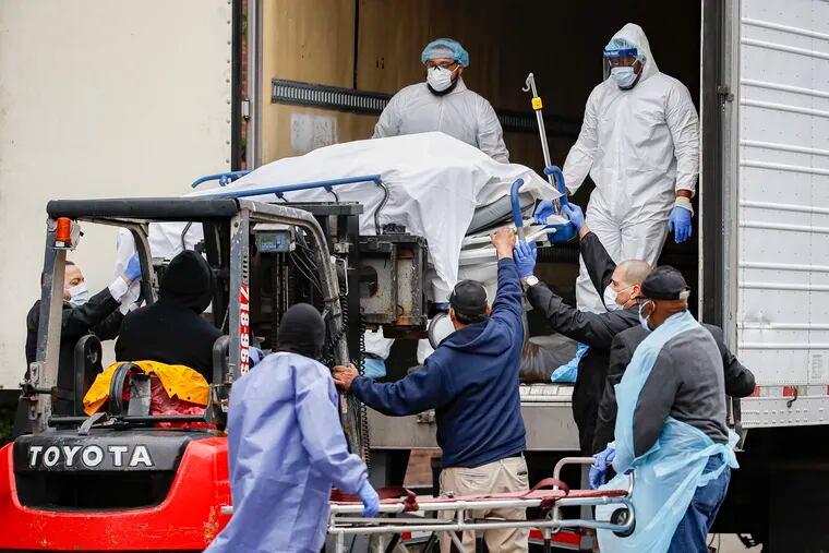 A body wrapped in plastic is unloaded from a refrigerated truck and handled by medical workers wearing personal protective equipment due to COVID-19 concerns at Brooklyn Hospital Center .