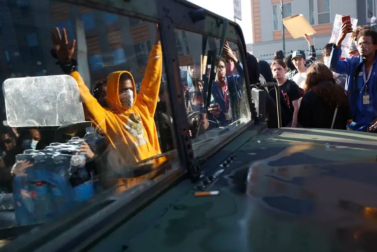 Protesters stand near a Minnesota National Guard vehicle Friday, May 29, 2020, in Minneapolis. Protests continued following the death of George Floyd, who died after being restrained by Minneapolis police officers on Memorial Day.
