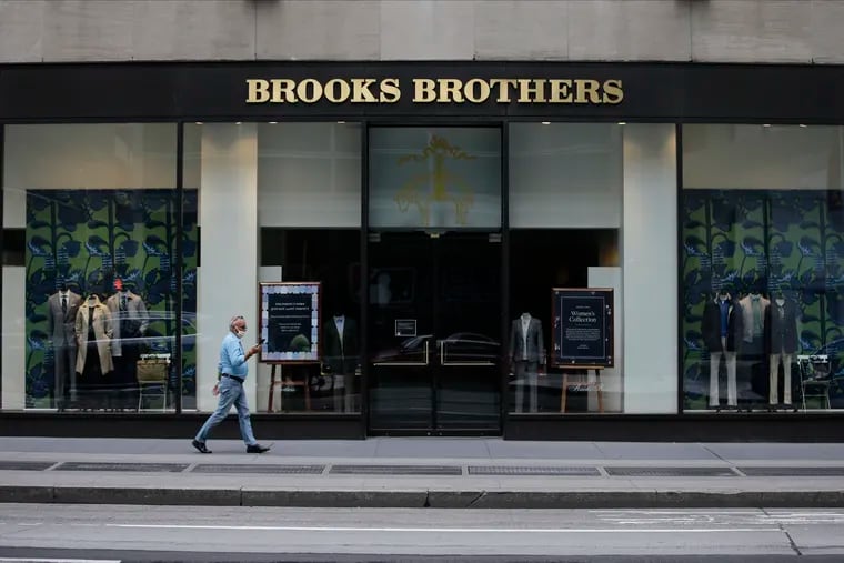 Pedestrians wearing protective masks walk past a Brooks Brothers location in a July 8, 2020 file photo, in New York. Brooks Brothers will be purchased for $325 million by a retail venture owned by licensing company Authentic Brands Group and mall owner Simon Property Group. It will continue running at least 125 Brooks Brothers retail locations as part of the deal. The 200-year-old New York-based clothier filed for Chapter 11 bankruptcy in July.  (AP Photo/Frank Franklin II, File)
